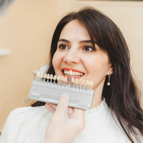 Young woman holding a tooth shade guide fan and smiling